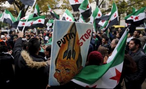 Demonstrators hold a placard and wave Syrian opposition flags as they protest against Russia's military operation in Syria in front of the Russian embassy in Berlin, Germany
