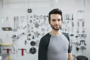 Portrait confident helicopter mechanic in front of tools