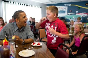 President Barack Obama shares his strawberry pie with a boy during a lunch stop at Kozy Corners restaurant in Oak Harbor, Ohio, July 5, 2012. (Official White House Photo by Pete Souza) This official White House photograph is being made available only for publication by news organizations and/or for personal use printing by the subject(s) of the photograph. The photograph may not be manipulated in any way and may not be used in commercial or political materials, advertisements, emails, products, promotions that in any way suggests approval or endorsement of the President, the First Family, or the White House.Ê